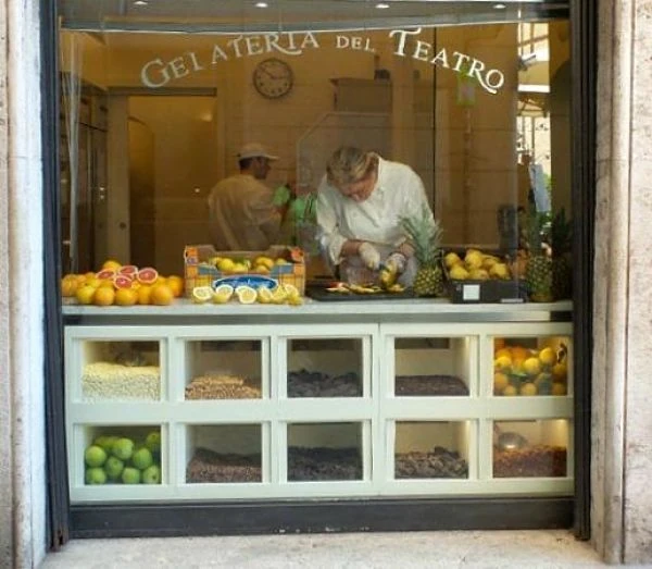 Interior de gelatería con vendedores y vitrinas de helado
