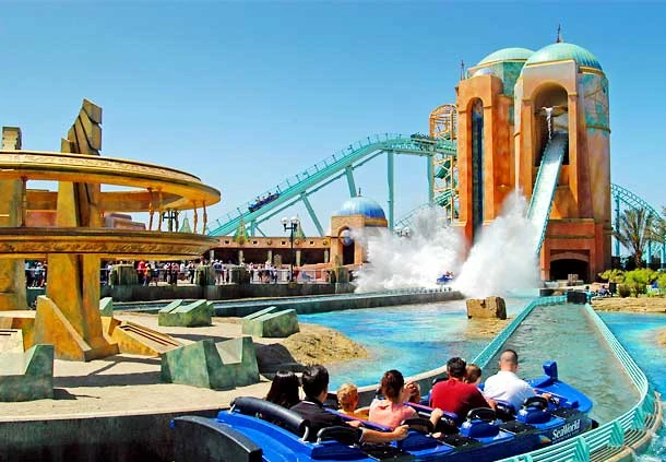 Parque acuático con toboganes coloridos, piscinas y visitantes en trampolines