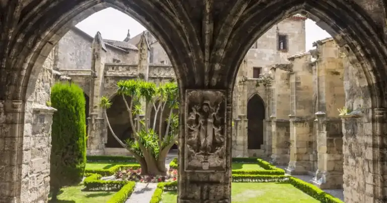 Claustro medieval con arcos de piedra y jardín verde interior