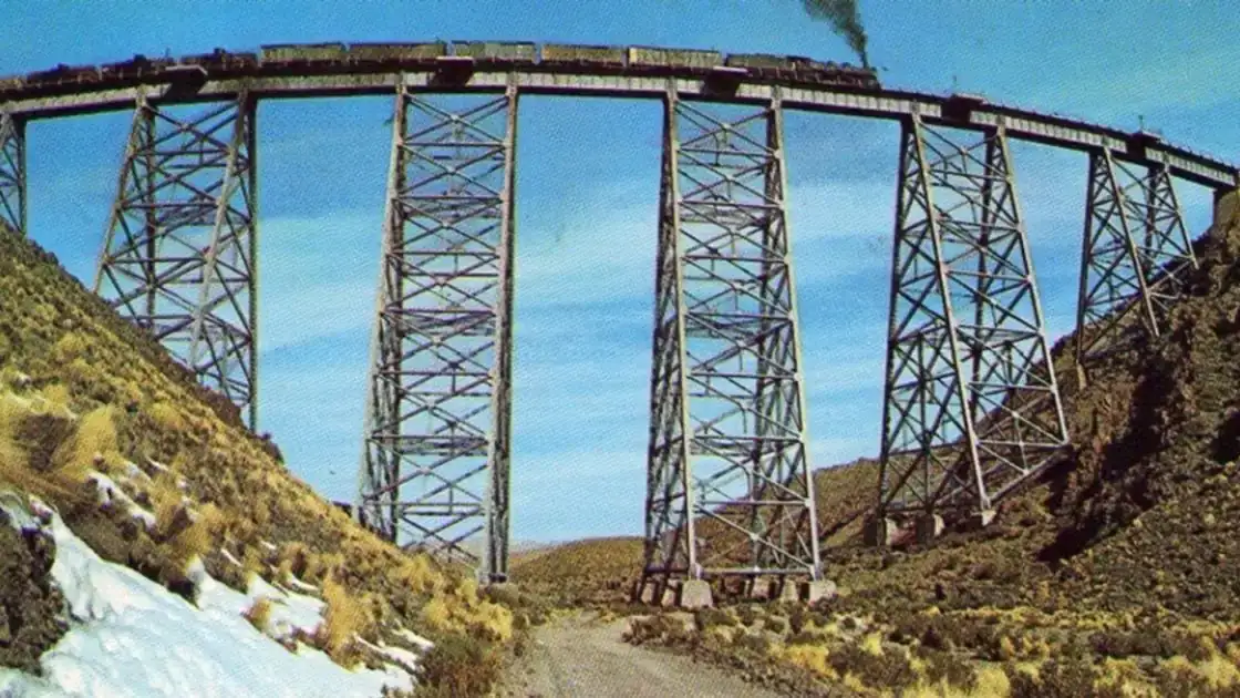 Puente ferroviario de hierro grande sobre paisaje de montañas nevadas