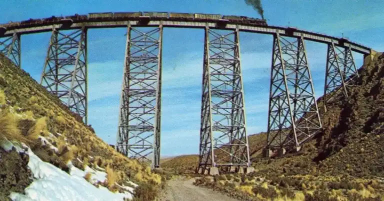 Puente ferroviario de hierro grande sobre paisaje de montañas nevadas