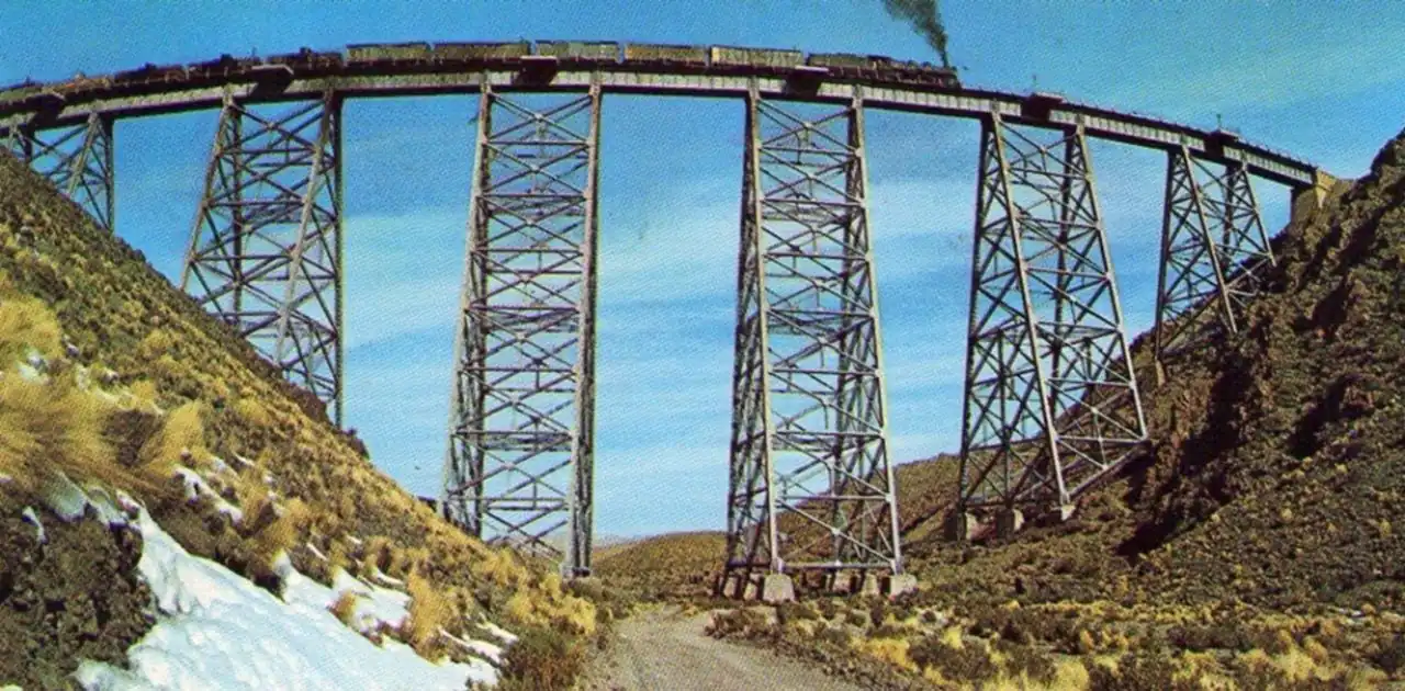 Puente ferroviario de hierro grande sobre paisaje de montañas nevadas