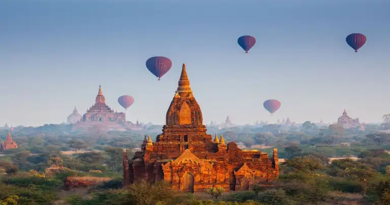 Templos dorados y globos aerostáticos sobre paisaje montañoso de Myanmar