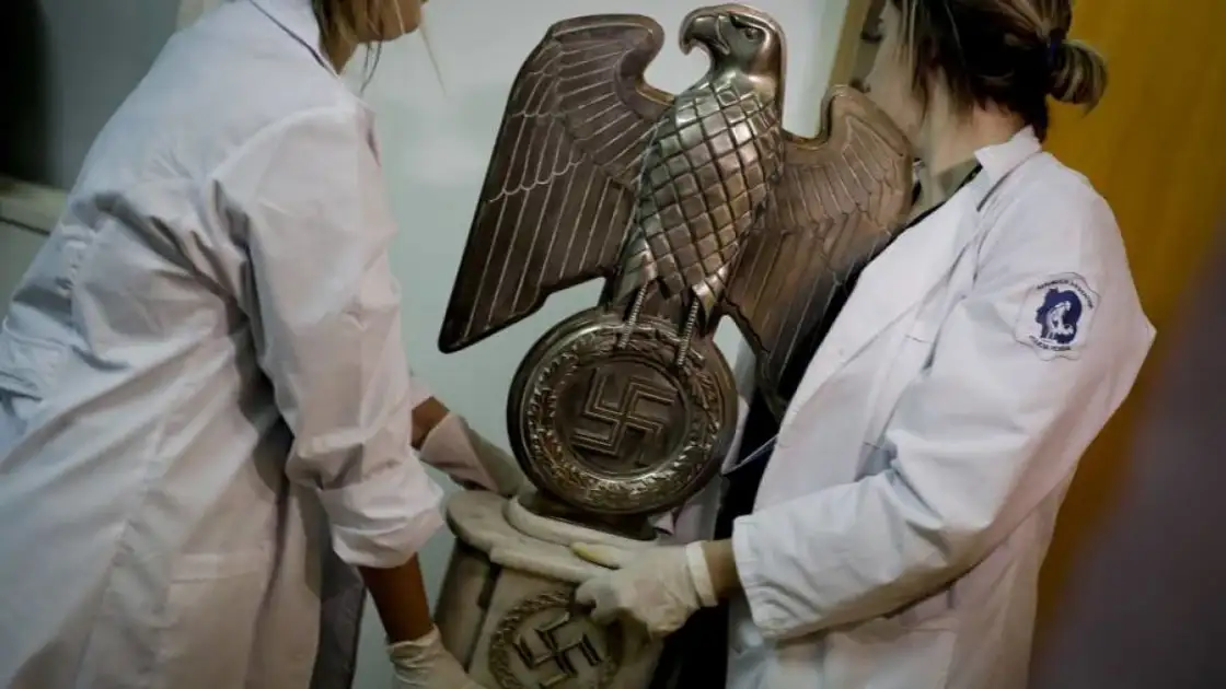 Dos personas sostienen emblema de águila de metal