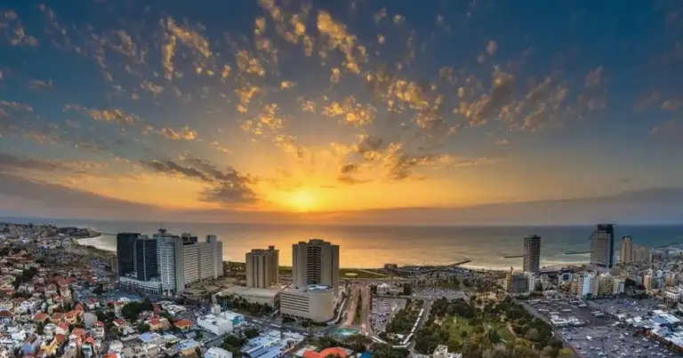 Foto érea de Tel Aviv, que muestra los edificios, el mar y el sol escondiéndose en el mediterraneo