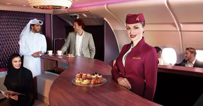 Interior de cabina de primera clase de avión con bar y personal de tripulación