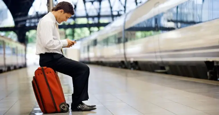Persona con maleta roja en estación de trenes