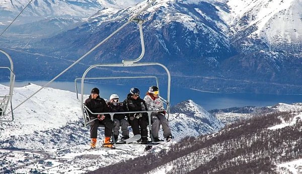 Grupos de personas en telesilla con vista panorámica de montaña nevada