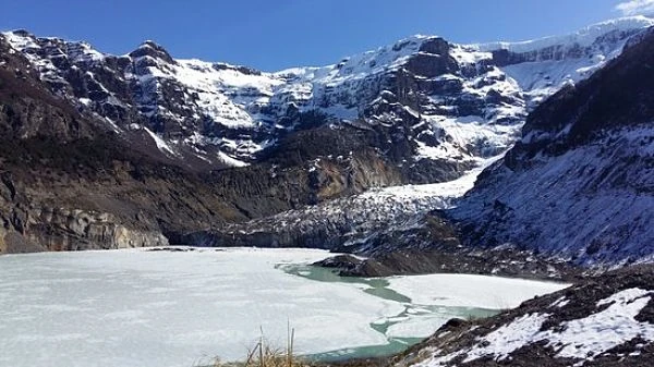 Valle nevado con glaciar blanco entre montañas nevadas y rocosas