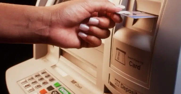 Mano insertando tarjeta en cajero automático con panel numérico visible