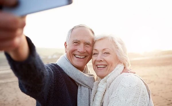 Dos personas mayores sonriendo frente a la cámara en un día soleado