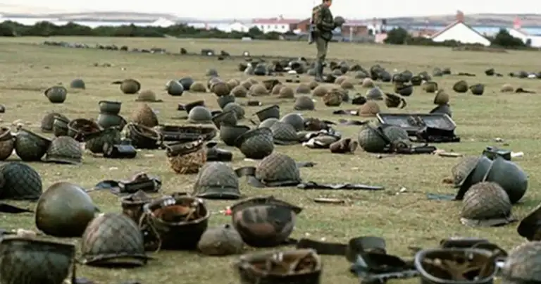 Soldado de pie entre cascos militares en campo