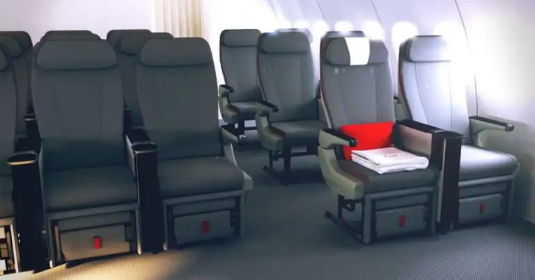 Fila de asientos de clase económica en cabina de avión, algunos en color rojo