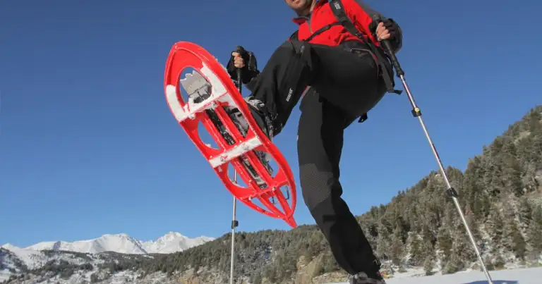Persona con raquetas de nieve en posición de esquí en montaña