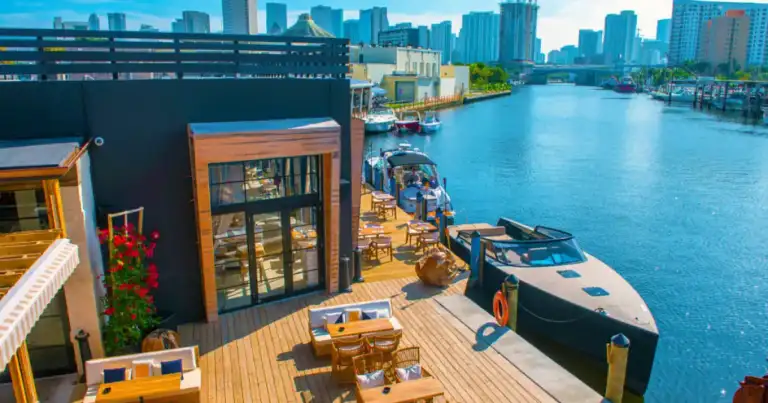 Terraza junto a río con botes pequeños y ciudad