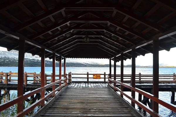 Muelle techado de madera con vista a lago azul