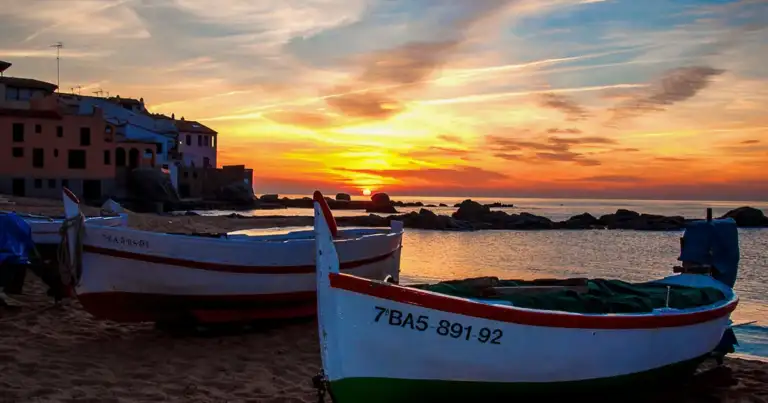 puerto de Calella de palafrugell, casas blancas, un bote y el atardecer