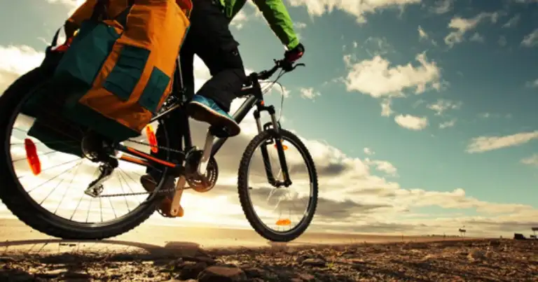 Persona en bicicleta con mochila en paisaje árido