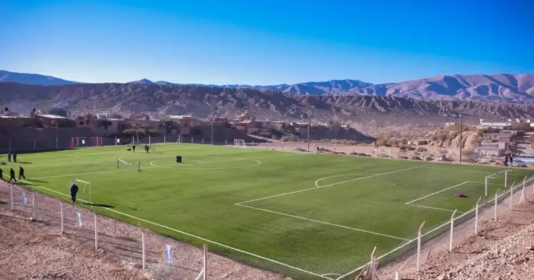 Cancha de fútbol en paisaje montañoso árido