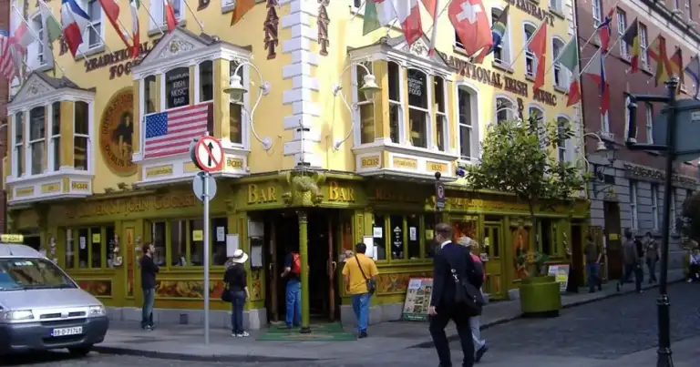 Calle comercial de Dublín con tiendas coloridas y banderas de múltiples países
