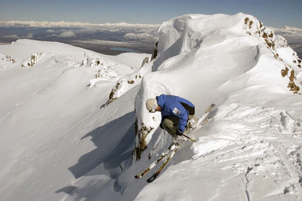 Esquiador descendiendo por nieve virgen en montaña con vista panorámica