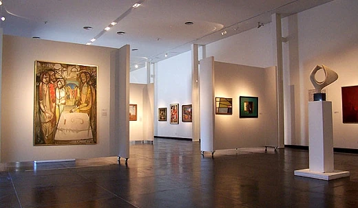 Sala de museo con cuadros en las paredes y una escultura blanca sobre un pedestal