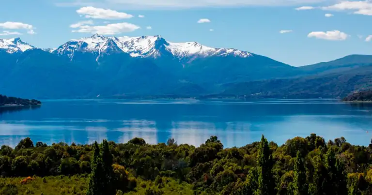 Montañas nevadas junto a lago azul con bosques