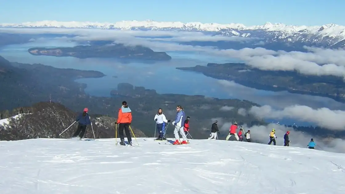Esquiadores en una pista nevada con vistas a lagos y montañas al fondo
