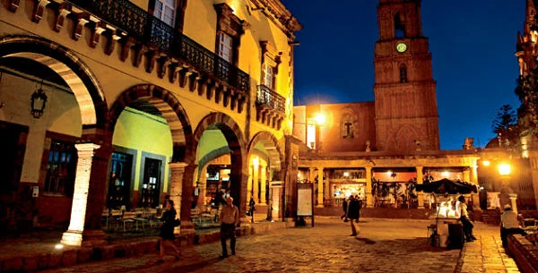 Calle colonial iluminada con personas disfrutando la vida nocturna
