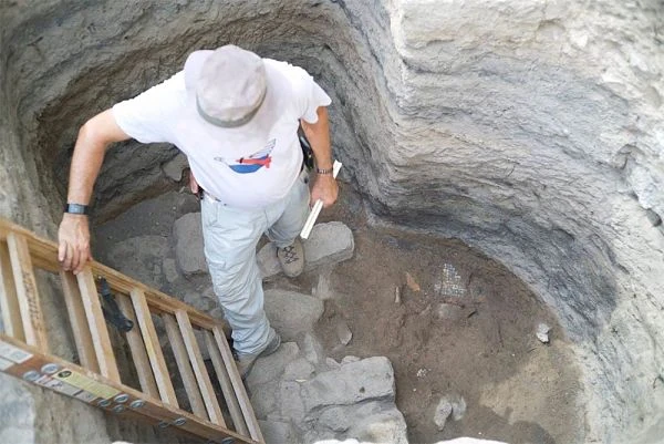 Person descending stone steps into underground archaeological excavation site