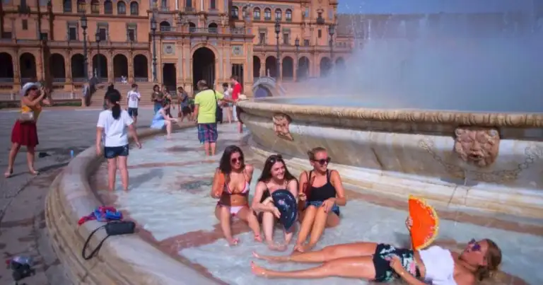 Personas refrescándose en una fuente durante una ola de calor