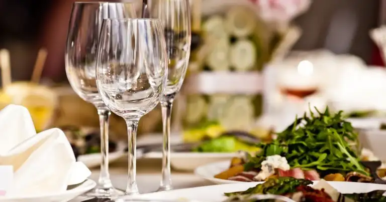 Copa de vino vacía en una mesa preparada con flores blancas y servilleta