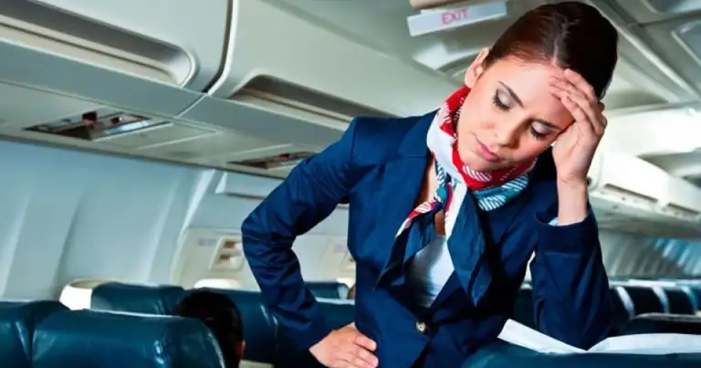 Azafata de uniforme azul descansando en el interior de un avión