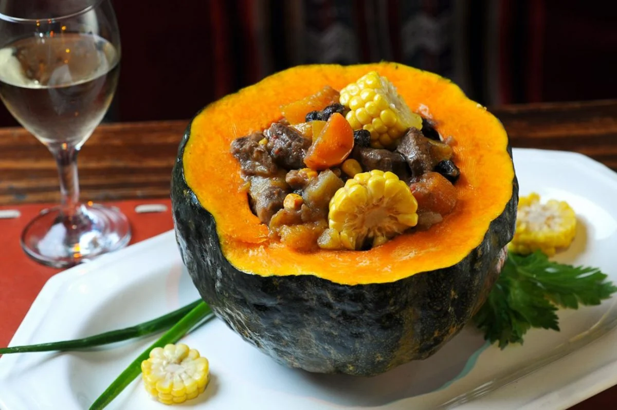 Carbonada criolla servida en zapallo: fusión de sabores autóctonos Zapallo redondo relleno con carbonada, acompañado de una copa de vino blanco