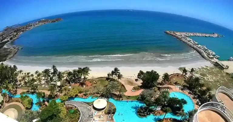 Bahía tropical semicircular con playa de arena blanca y complejos costeros