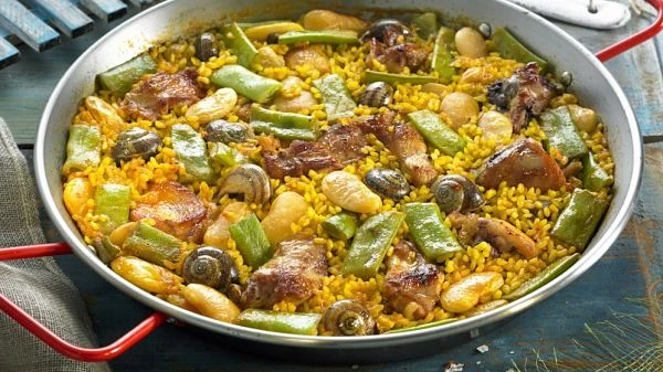 La auténtica paella valenciana Paella valenciana tradicional con arroz, verduras y mariscos en paellera