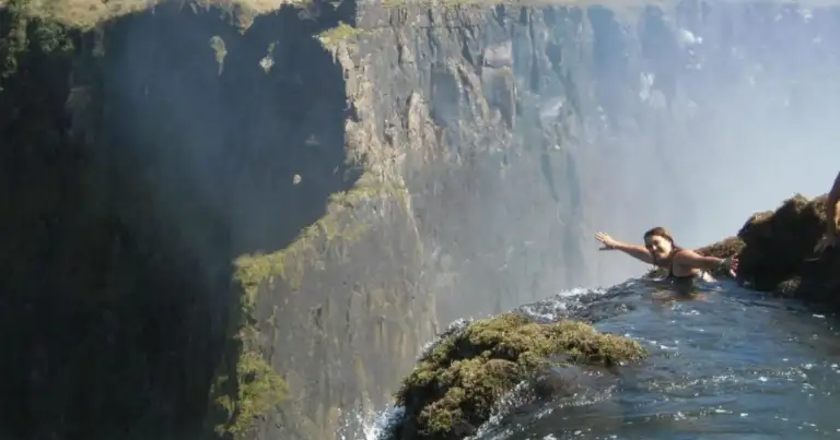Nadador en una piscina natural en el borde de un acantilado
