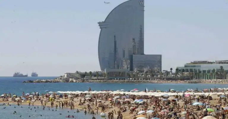 Playa abarrotada de turistas con el hotel W Barcelona al fondo