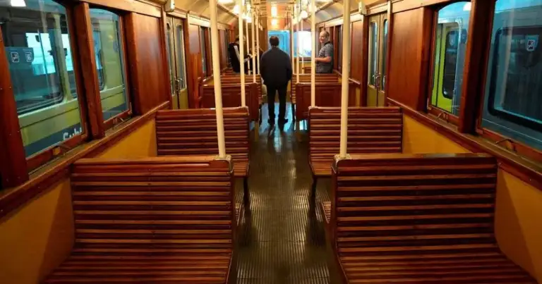 Interior de vagón antiguo de subte con asientos de madera roja