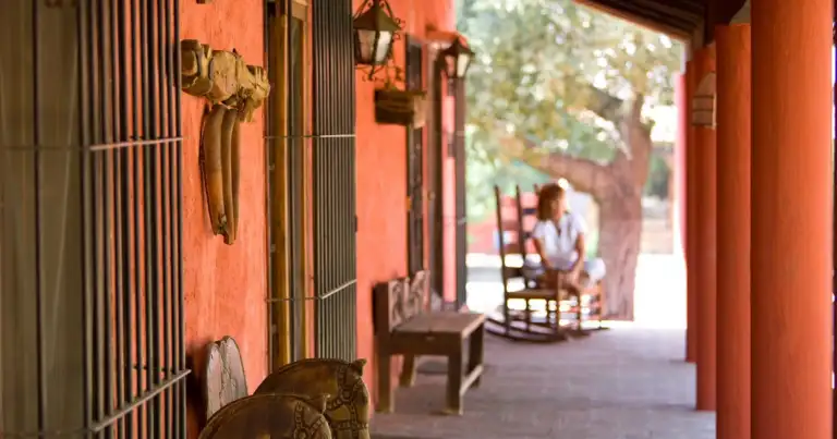 Porche de una casa roja con rocking chairs en un pueblo mexicano
