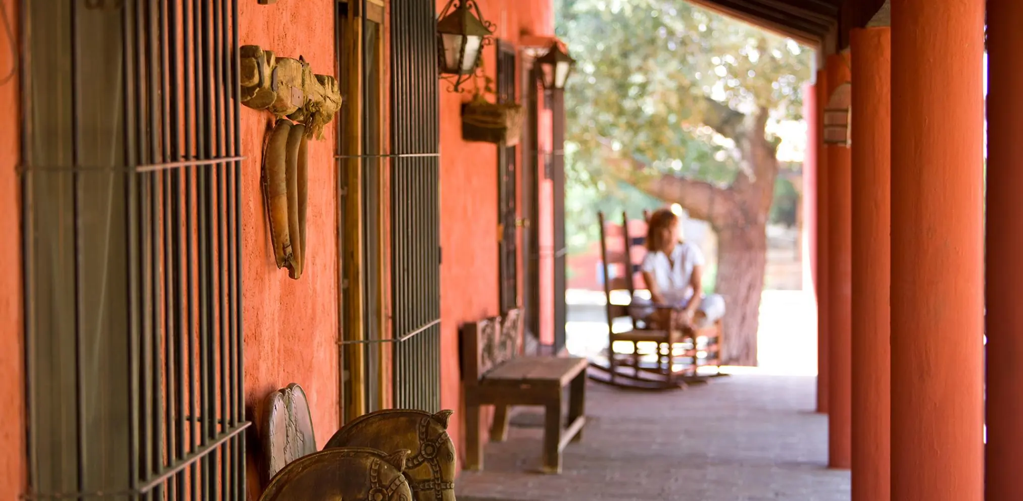 Porche de una casa roja con rocking chairs en un pueblo mexicano