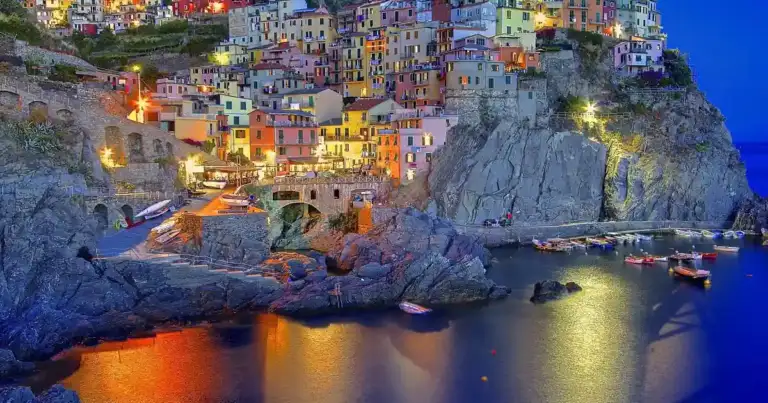 Manarola, casas blancas y botes iluminados en la playa