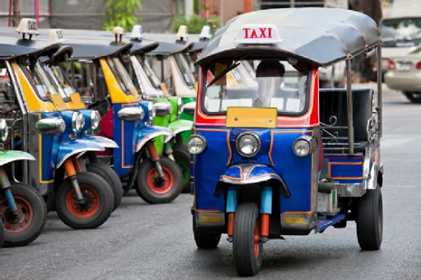 Tuk-tuks azules y rojos estacionados en fila esperando pasajeros