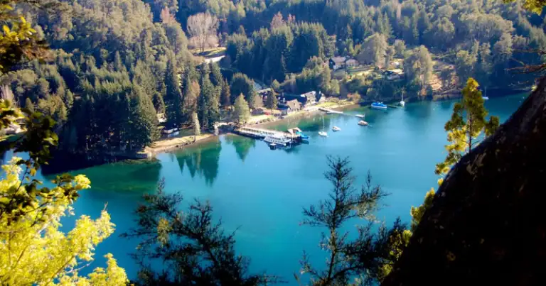 Lago turquesa rodeado de bosques y viviendas junto a la orilla