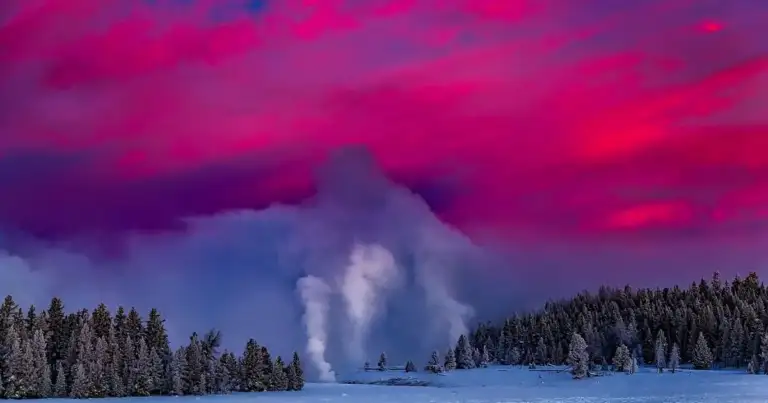 Geiser humeante en paisaje nevado con cielo púrpura