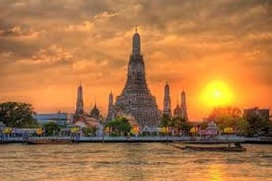 Templo de piedra con torres puntiagudas al atardecer junto a río