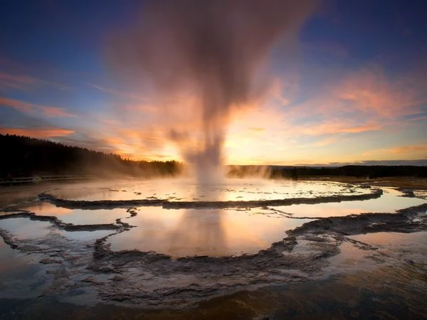 Géiser expulsando columna de agua caliente al atardecer