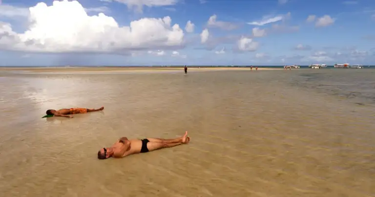 Personas disfrutando en piscina natural de agua turquesa en playa