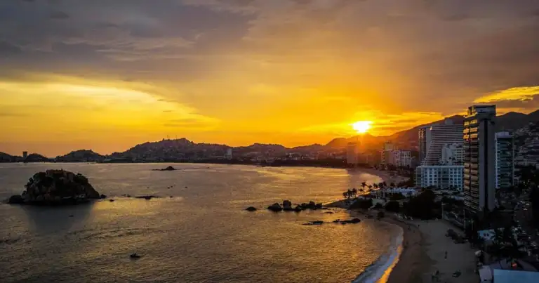 Playa y bahía al atardecer con edificios costeros en Acapulco