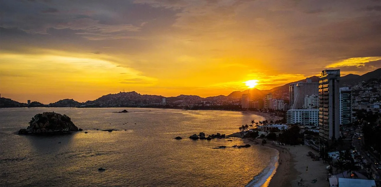 Playa y bahía al atardecer con edificios costeros en Acapulco